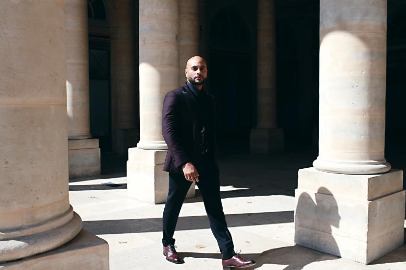 Man in black suit between white pillars